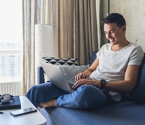 A young man smiling while using his laptop