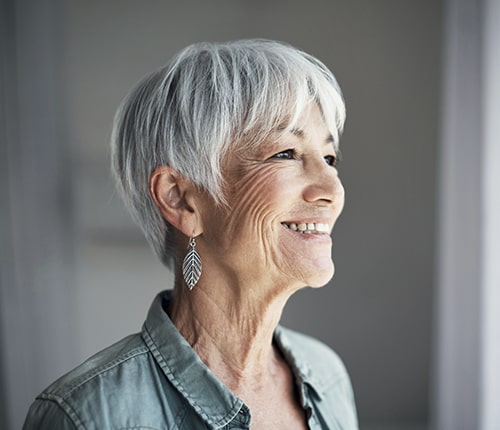 A mature woman smiling after her dental implants in Muncie, IN