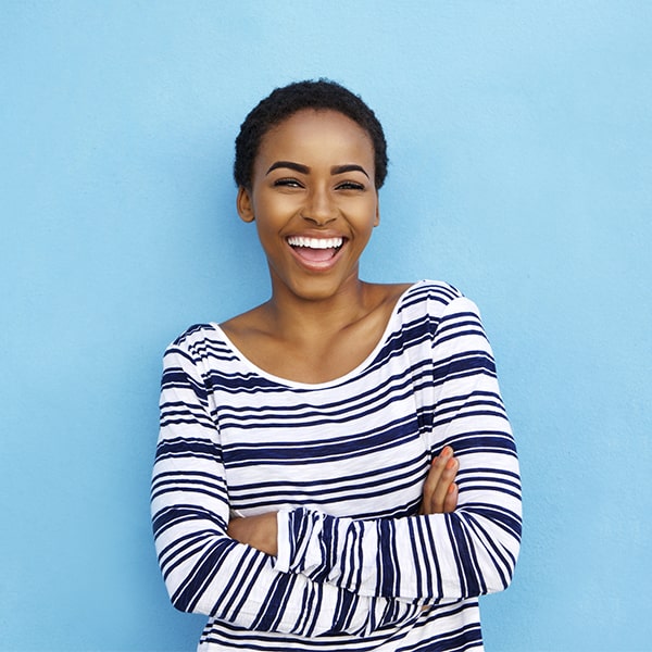 A woman crossing her arms smiling after her teeth whitening treatment
